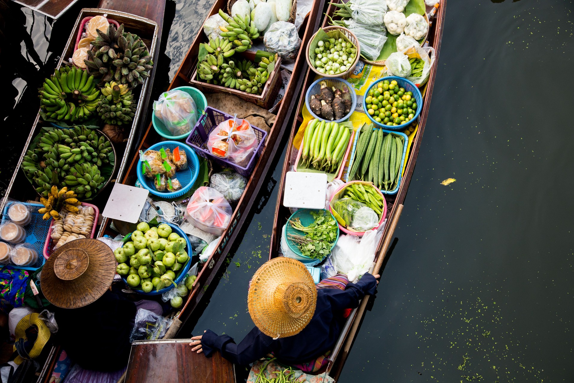 Women selling vegetables and fruit from their canoes at the Tha Kha floating market in Thailand.